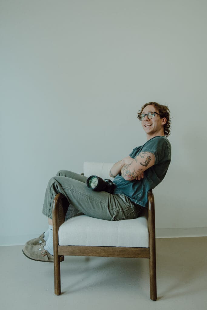 photo of gavin sitting sideways on a chair with his camera sitting on his lap.