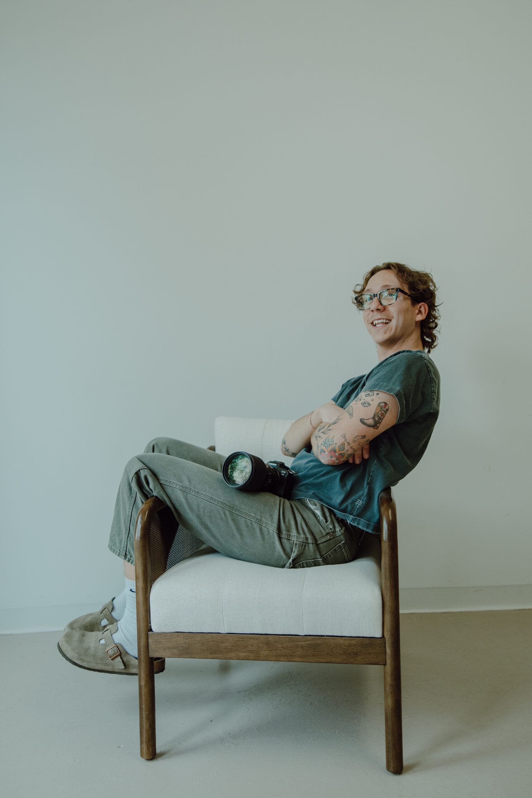 photo of gavin sitting sideways on a chair with his camera sitting on his lap.