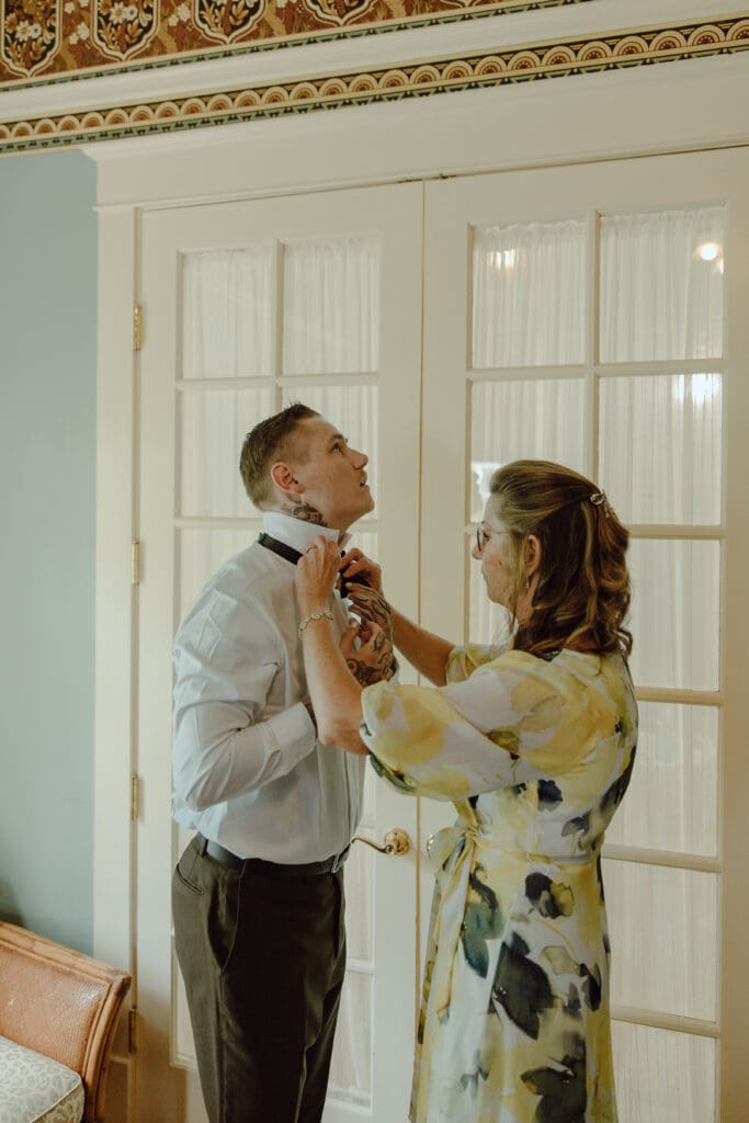 Grooms mom tying his tie 