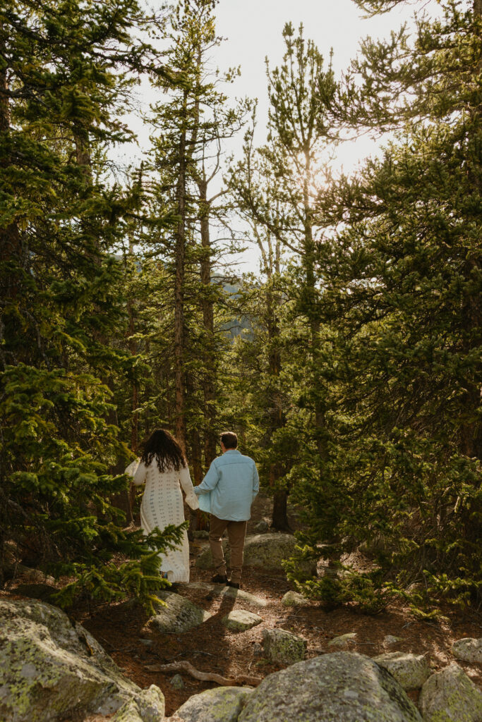 man and woman walking in forest during engagement session