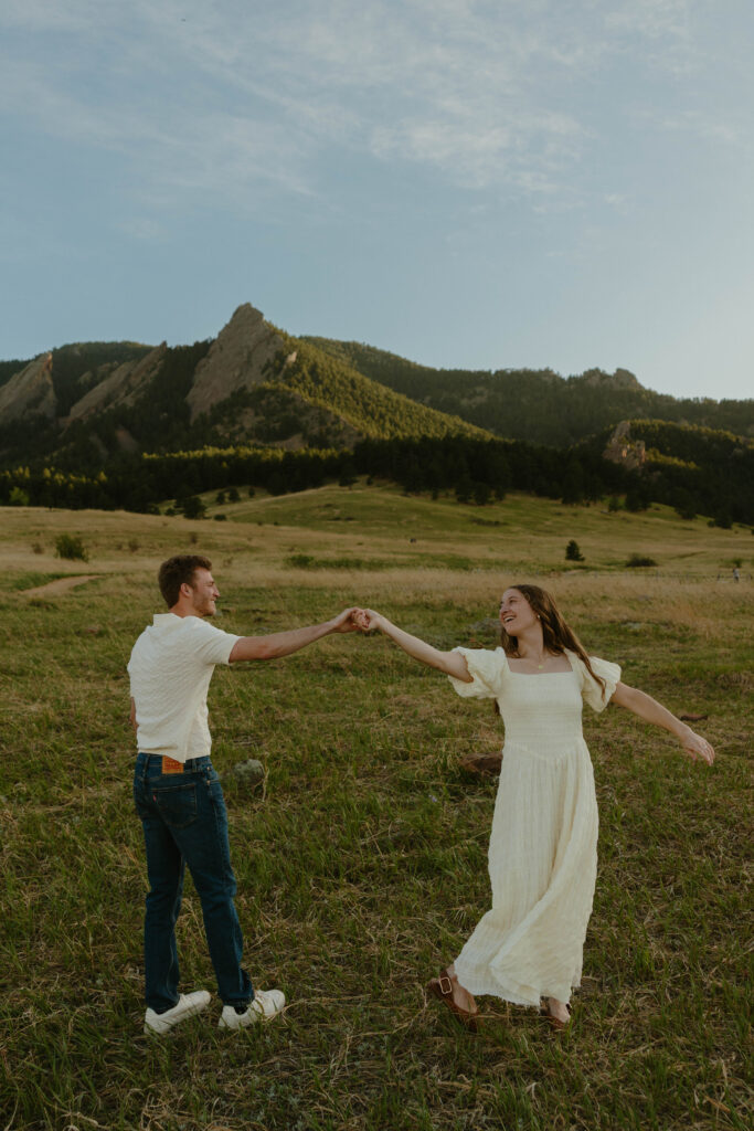 Couple twirling in the mountains during engagement photos