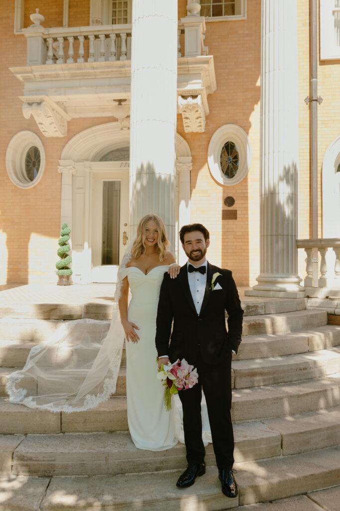 bride and groom smiling in front of Grant Humphreys Mansion in Denver